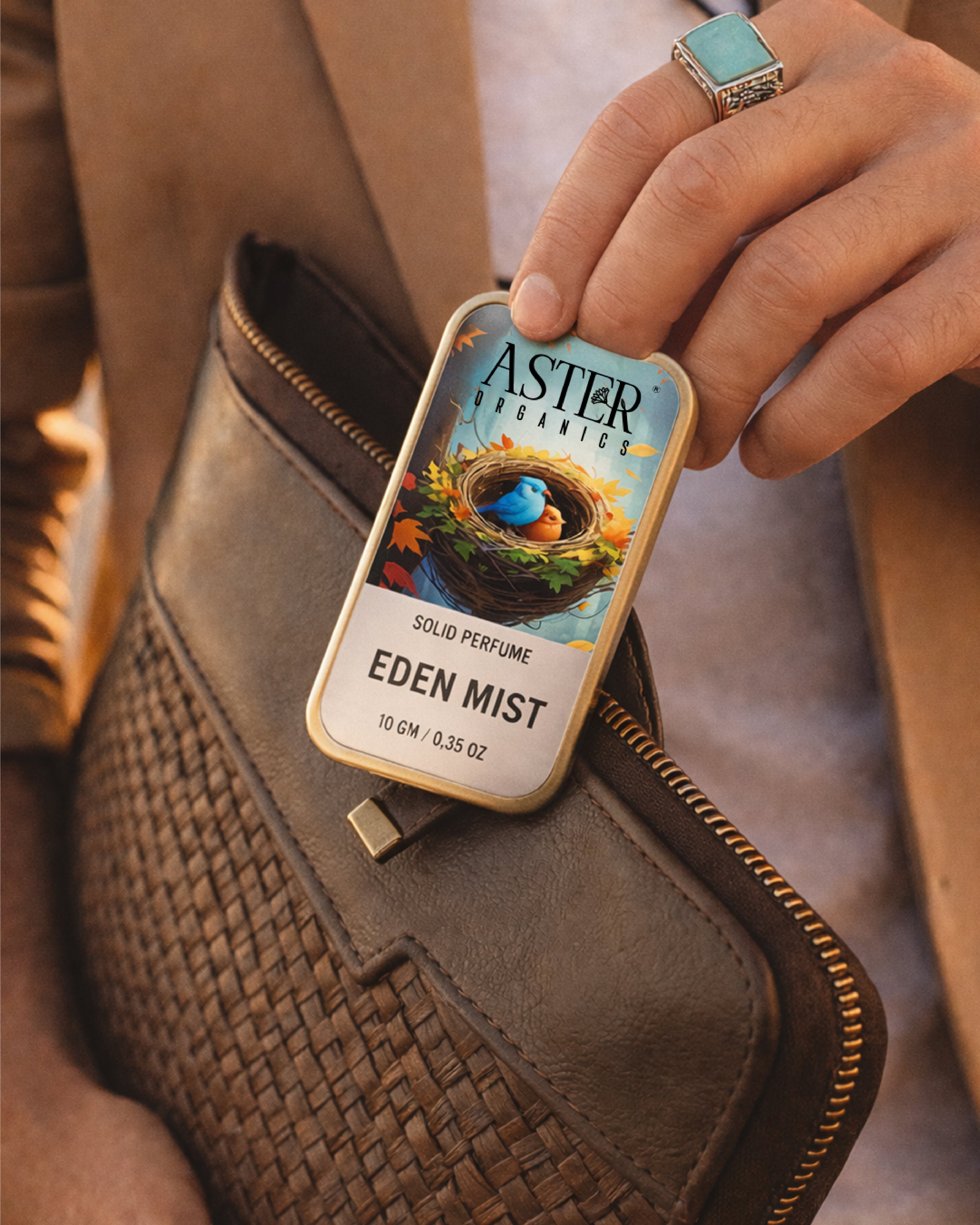 Person holding an Aster & Aster solid perfume packaging with 'Eden Mist' on a textured surface.