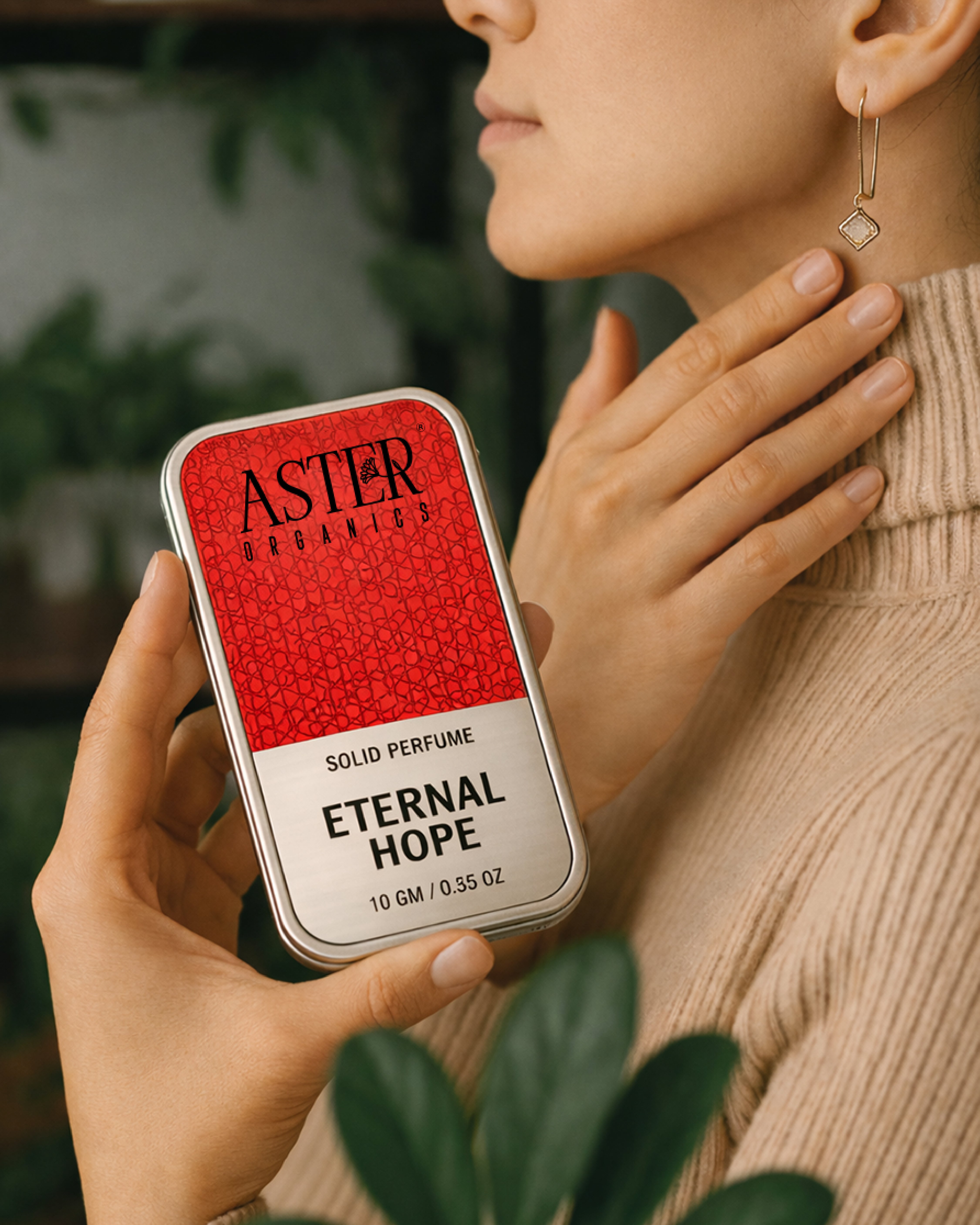 Person holding a red and silver 'Aster Organics' solid perfume tin labeled 'Eternal Hope'.