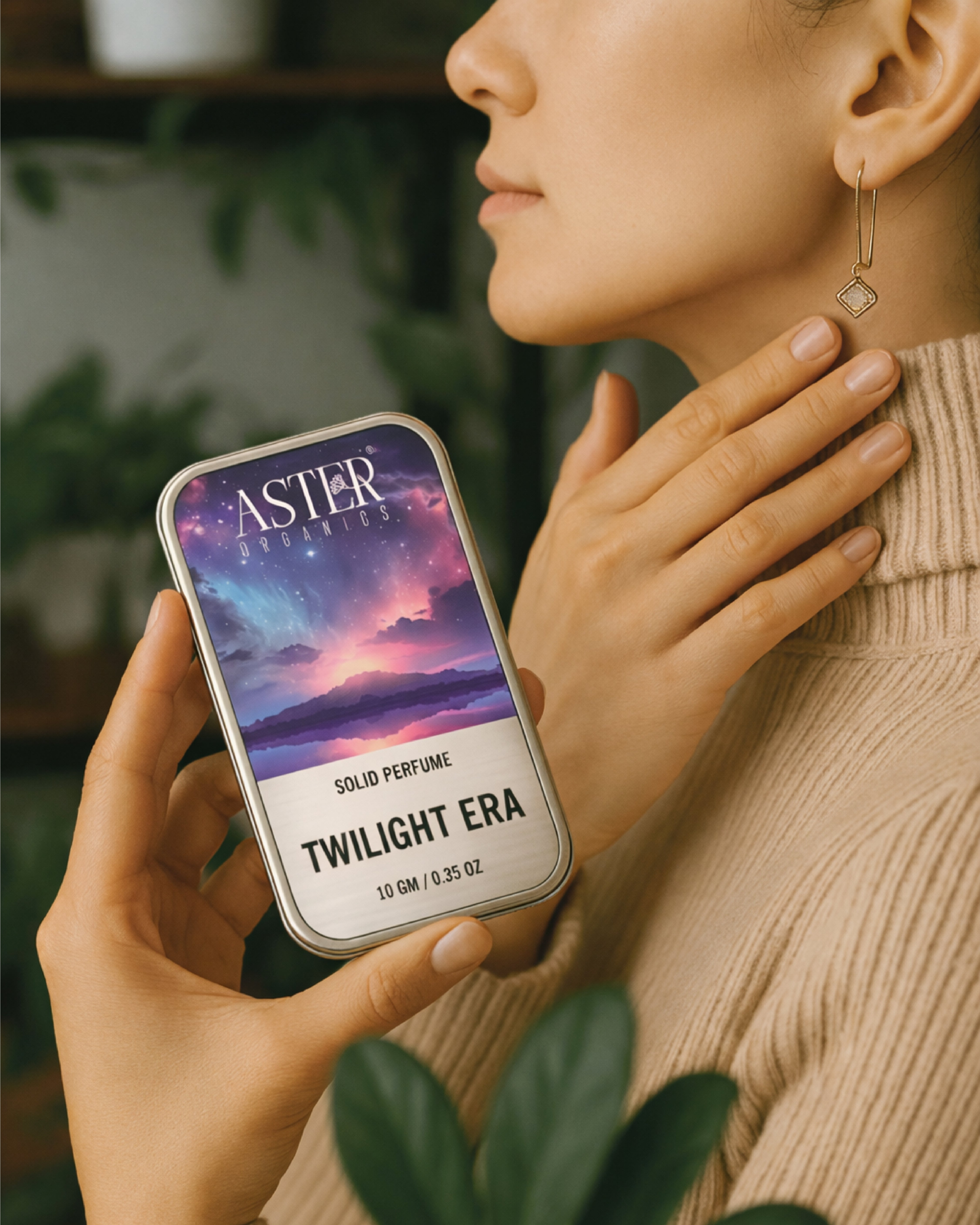 Person holding an Aster Twilight Era solid perfume tin with a blurred background